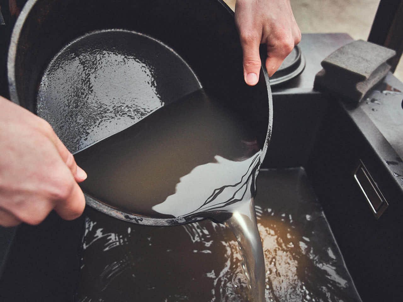 Dutch Oven reinigen: Schmutzwasser wird aus Dutch Oven in Spüle gegossen