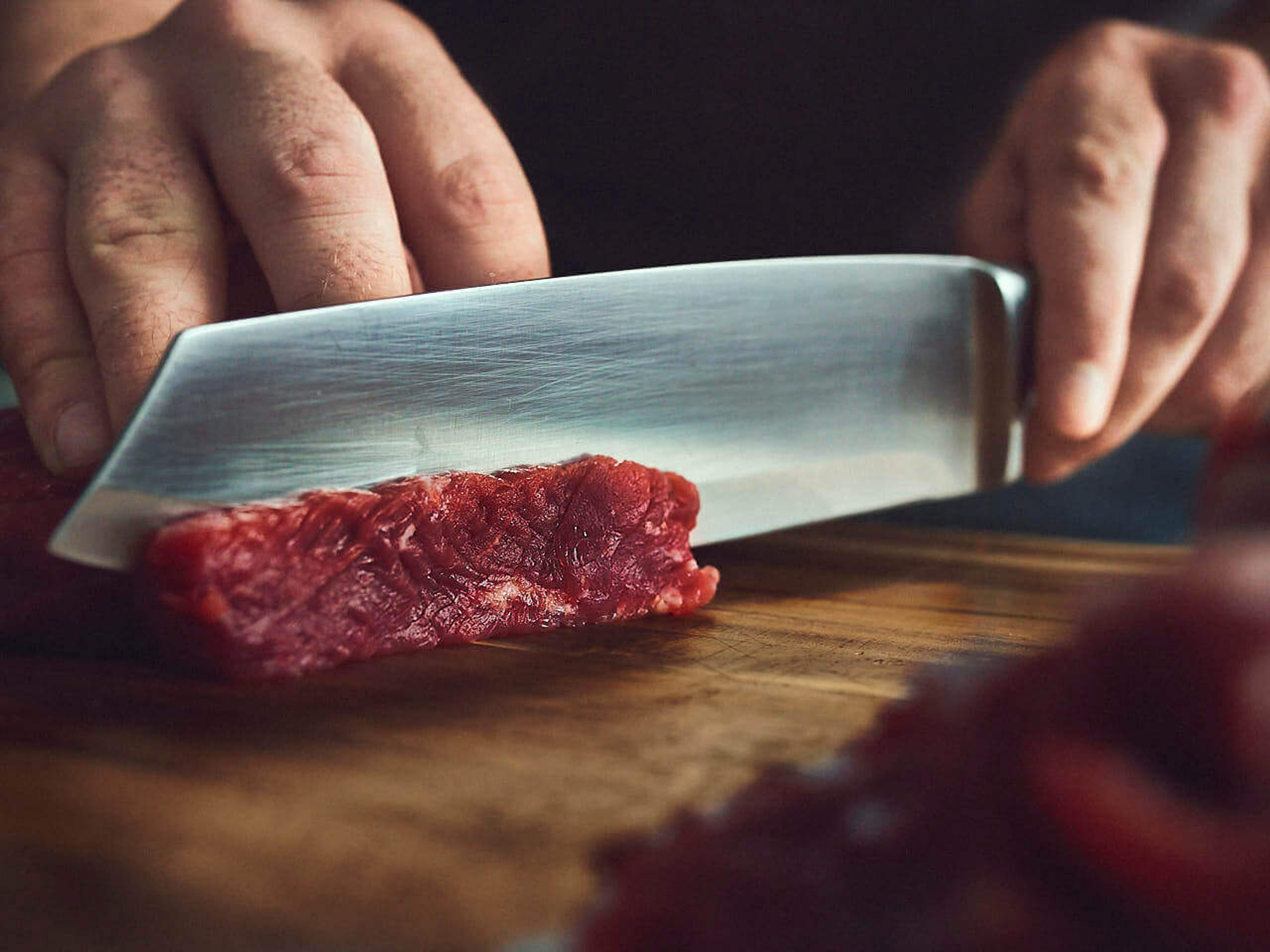 Rindfleisch wird mit Messer in dünne Streifen geschnitten